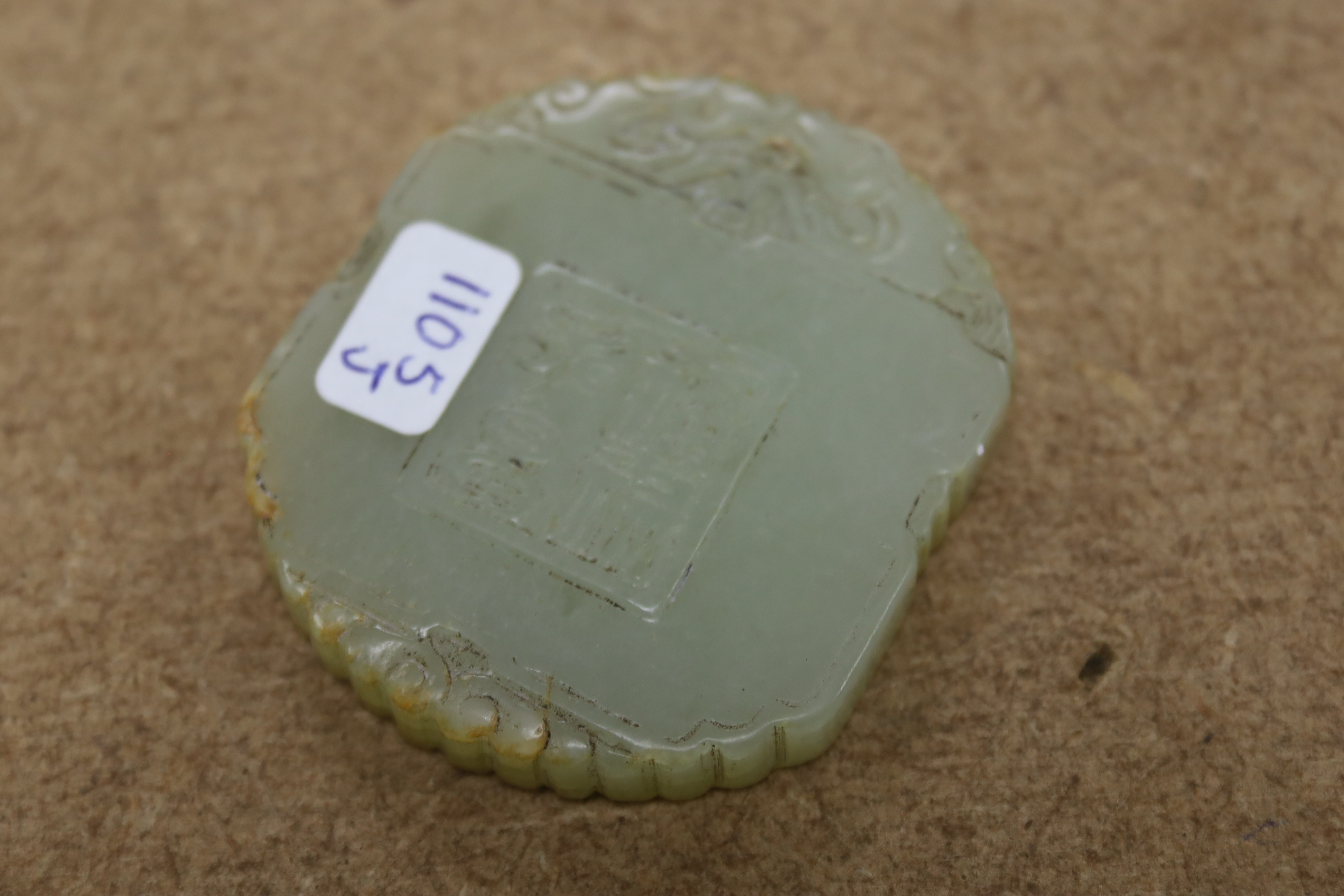A Chinese pale celadon jade plaque, boy and bats, 5cm wide